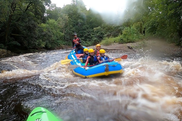 Group rafting on a river with trees in the background.